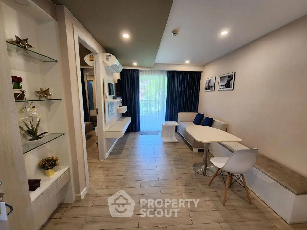 Modern living room with stylish decor and natural light, featuring a cozy seating area and elegant shelving.