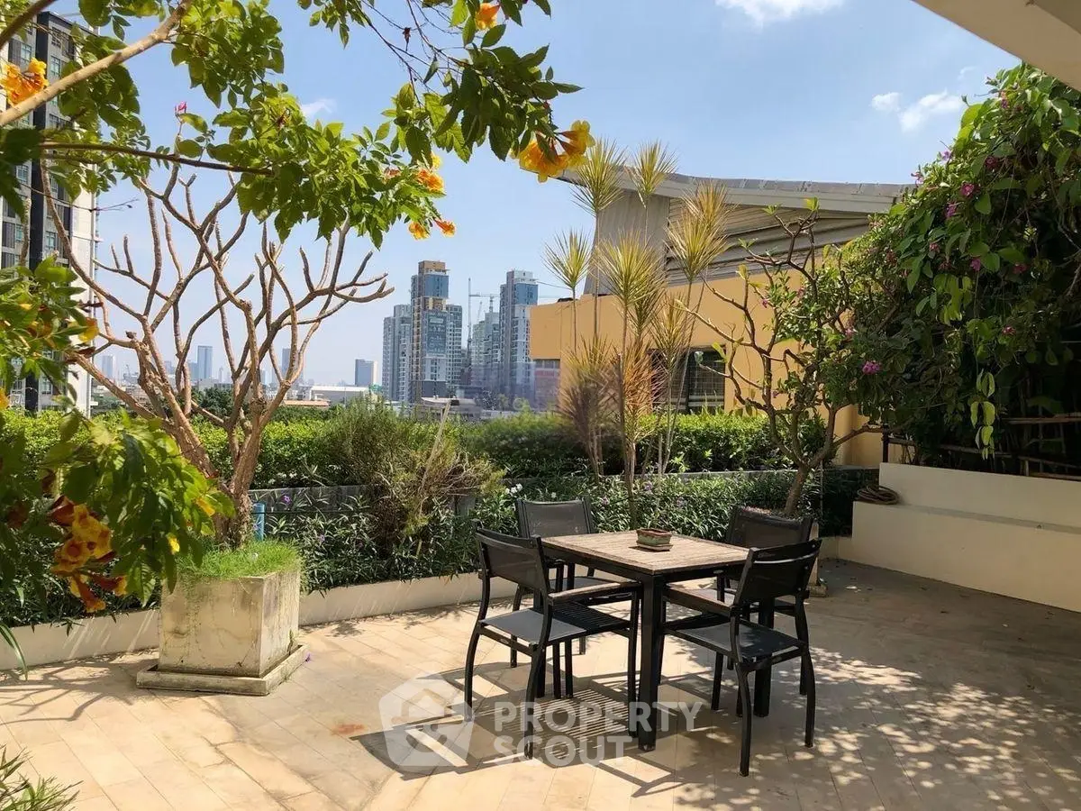 Spacious rooftop terrace with city skyline view and lush greenery, perfect for outdoor dining and relaxation.