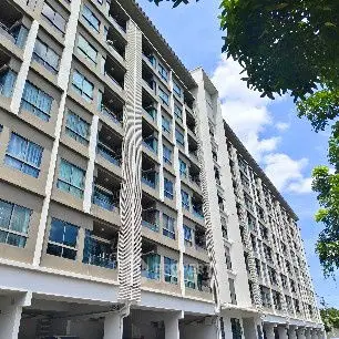 Modern multi-story residential building with large windows and blue sky backdrop.