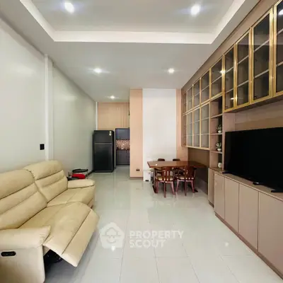 Modern living room with sleek furniture and open layout, featuring a cozy dining area and stylish cabinetry.