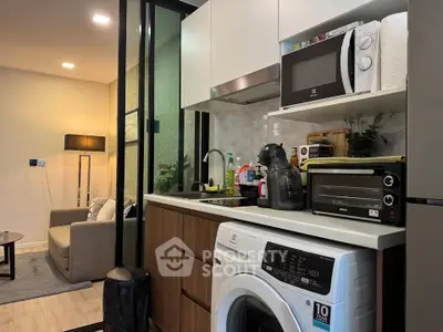 Modern compact kitchen with washing machine and microwave in stylish apartment