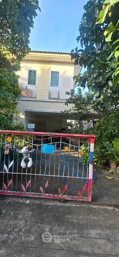 Charming two-story house with lush garden and gated entrance, perfect for family living.