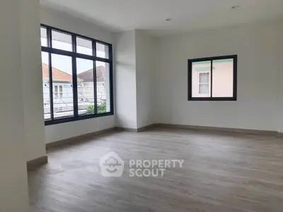 Spacious empty room with large windows and wooden flooring, perfect for customization.