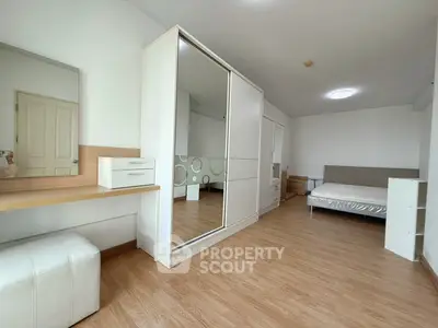 Spacious modern bedroom with wooden flooring and sleek furniture