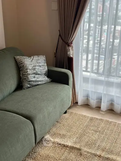 Cozy living room with green sofa and city view through large window.