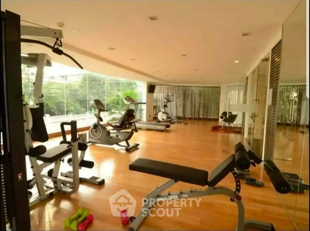 Spacious gym with modern equipment and large windows offering a serene view, perfect for fitness enthusiasts.