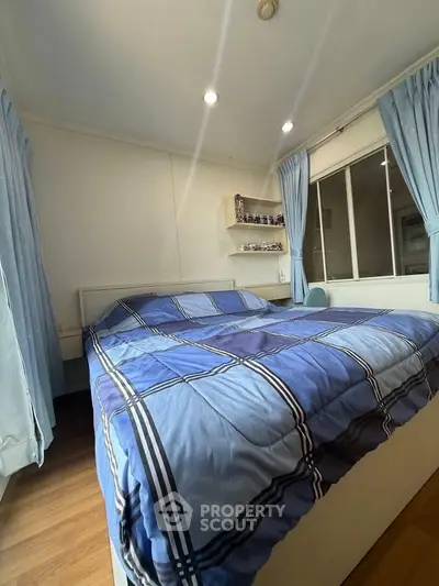 Cozy bedroom with blue plaid bedding and natural light from large windows.