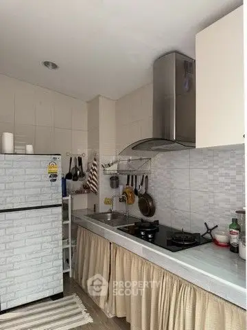 Charming kitchen with gas stove and modern hood, featuring a cozy closed layout and ample storage space.