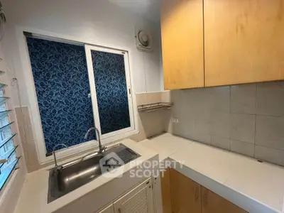 Cozy kitchen with closed layout and modern cabinetry, featuring a sleek stainless steel sink and tiled backsplash.