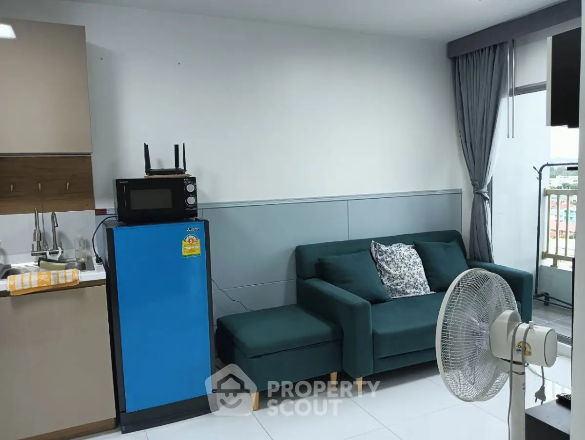 Modern living room with blue sofa, compact kitchen, and balcony view.