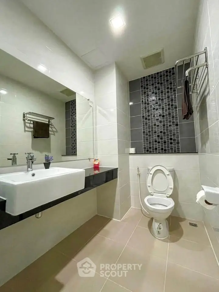 Modern bathroom with sleek design, featuring a large mirror and contemporary fixtures.