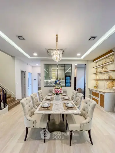 Elegant dining room with plush chairs and modern chandelier in a luxurious home.