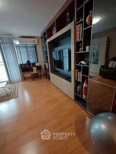 Spacious living room with modern entertainment center and hardwood flooring.