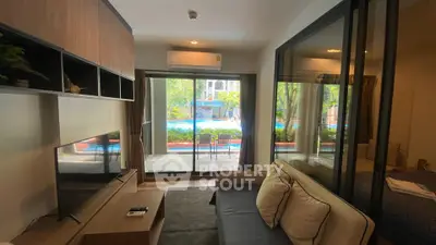 Modern living room with pool view, sleek furniture, and large glass doors.