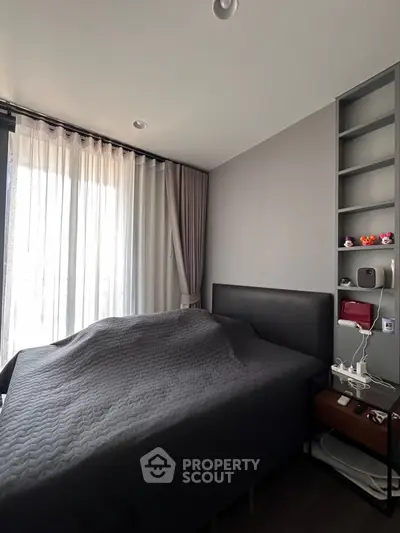 Modern bedroom with sleek design and natural light through large window.