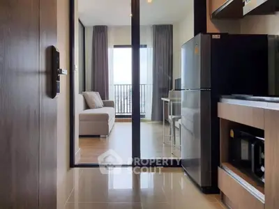 Modern apartment interior with open kitchen and cozy living area leading to a balcony with city view.
