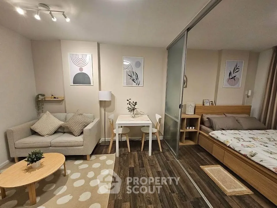 Chic studio apartment with modern decor, cozy living area, and stylish bedroom separated by sliding glass doors.