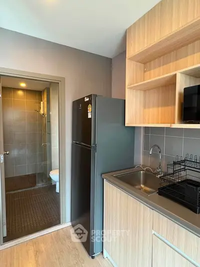 Modern kitchen with sleek cabinetry and adjacent bathroom in a compact apartment layout.