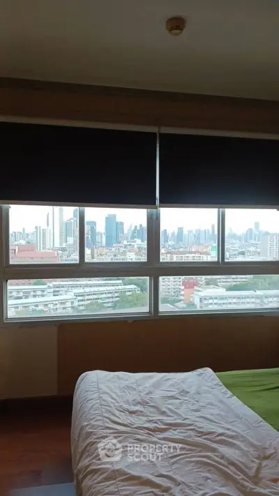 Spacious bedroom with stunning city view through large windows.
