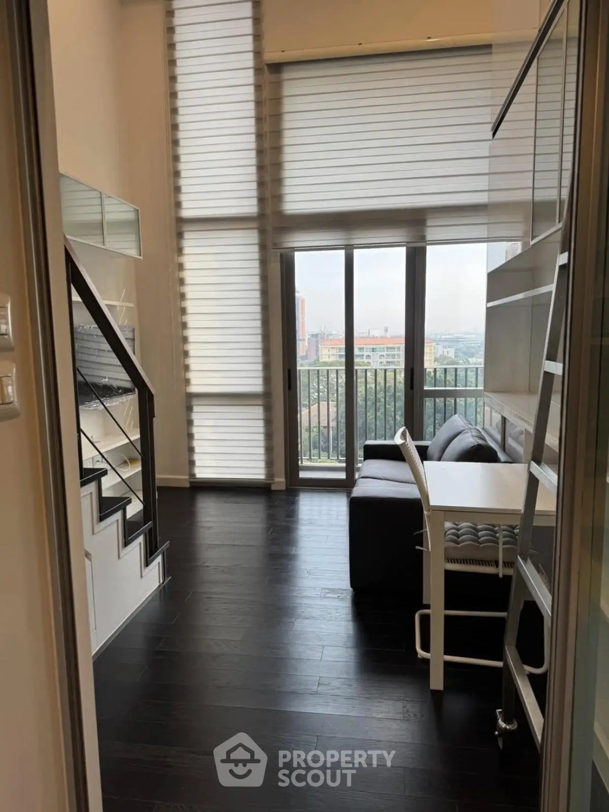 Modern loft-style living room with high ceilings and large windows offering a stunning view.