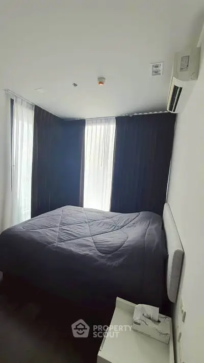 Cozy bedroom with modern decor and natural light, featuring a comfortable bed and air conditioning.