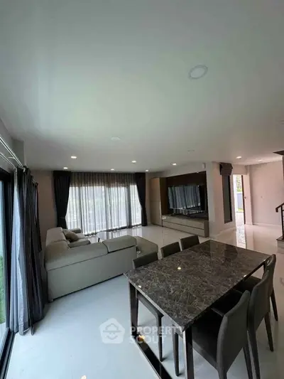 Spacious modern living room with elegant dining area and large windows.