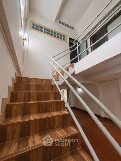 Modern staircase with wooden steps and sleek metal railing in a contemporary home interior.