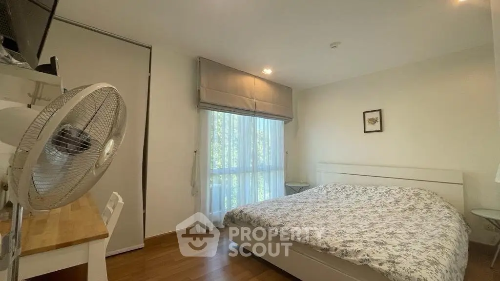 Cozy bedroom with large window and modern decor, perfect for relaxation.
