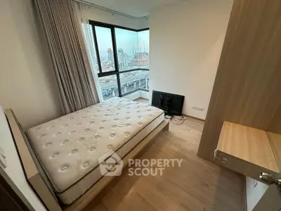 Modern bedroom with city view, featuring a comfortable bed and large windows for natural light.
