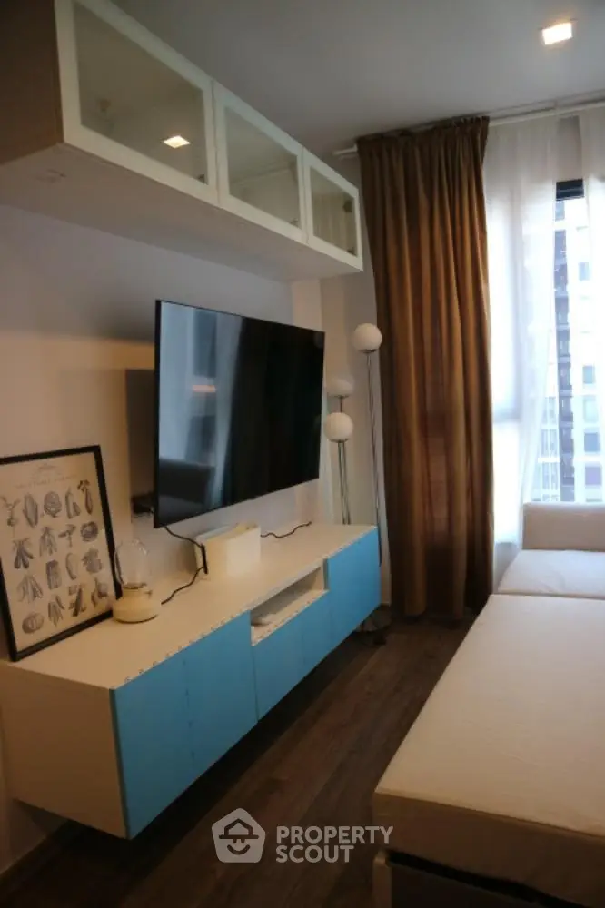 Modern living room with sleek TV setup and stylish decor in urban apartment.