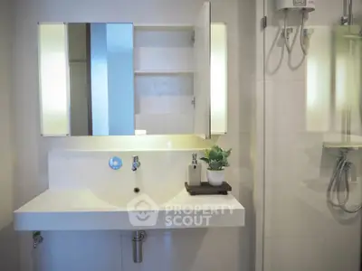 Modern bathroom with sleek white sink and illuminated mirror cabinet