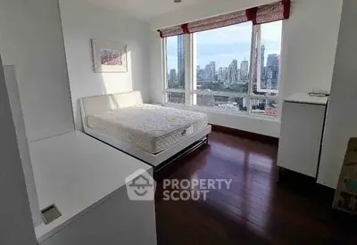 Spacious bedroom with city view and large windows in modern apartment.