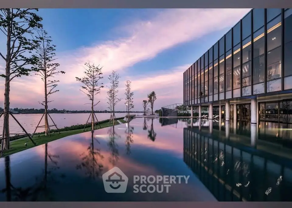 Stunning modern building with infinity pool and serene lakeside view at sunset.