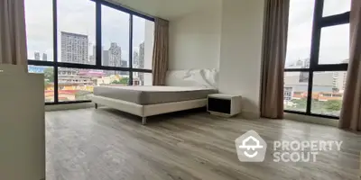 Spacious bedroom with large windows offering stunning city views in modern apartment