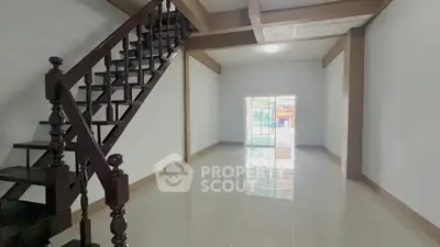 Spacious open-plan living area with elegant staircase and glossy tiled floors
