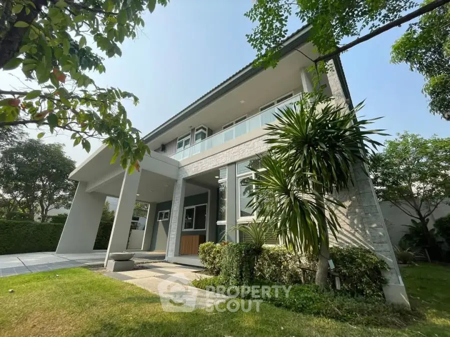 Modern two-story house with lush garden and sleek architectural design.