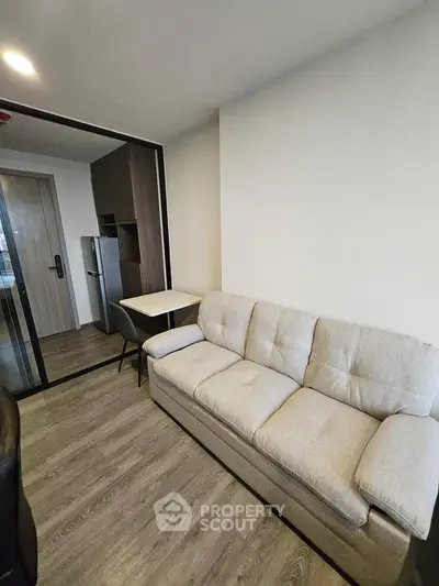 Modern living room with cozy sofa and sleek kitchen area in open layout apartment.