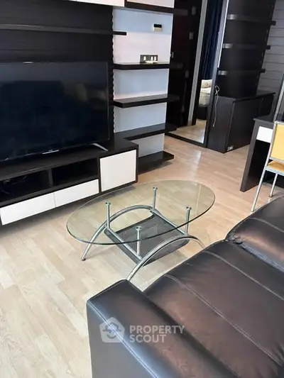 Modern living room with sleek black leather sofa and glass coffee table