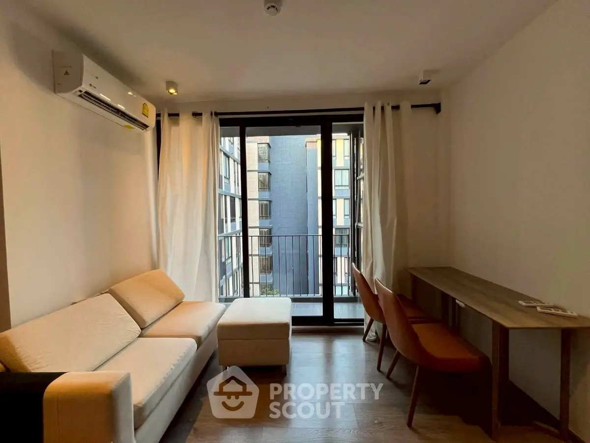 Modern living room with balcony view, featuring sleek furniture and natural light.