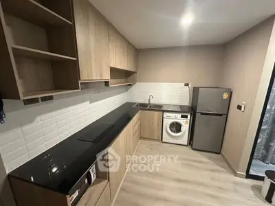 Modern kitchen with sleek cabinetry, washing machine, and compact fridge in a stylish apartment.