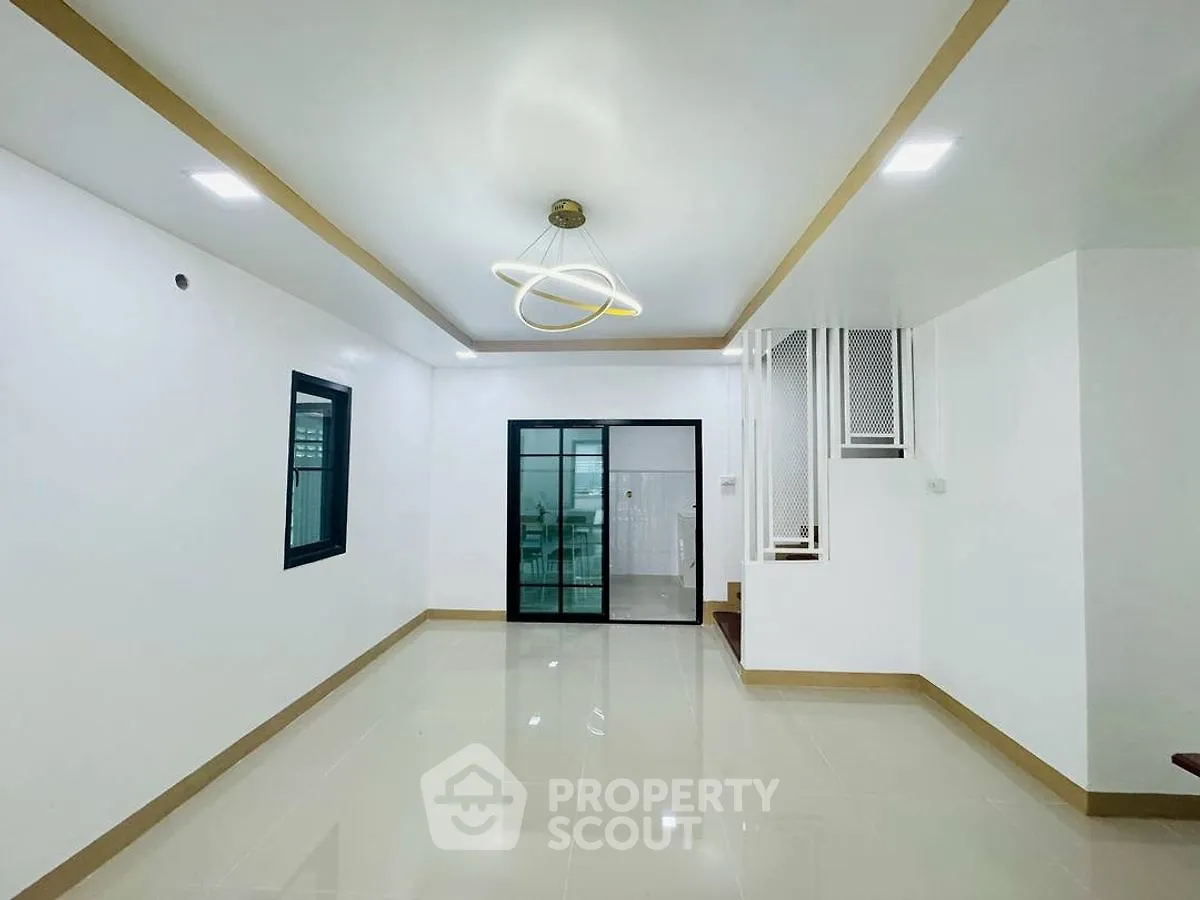 Spacious modern living room with sleek lighting and tiled flooring, perfect for contemporary living.