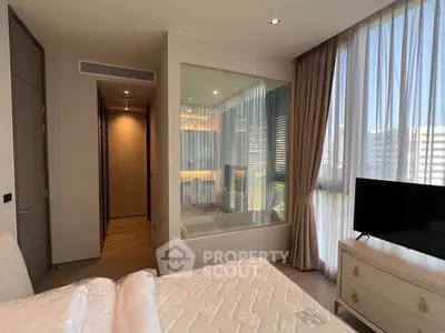 Luxurious bedroom with large windows and modern decor in high-rise apartment.