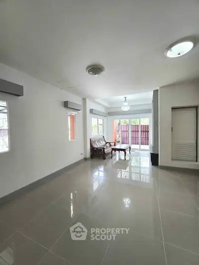 Spacious living room with glossy tiled floors and elegant wooden furniture, ample natural light.