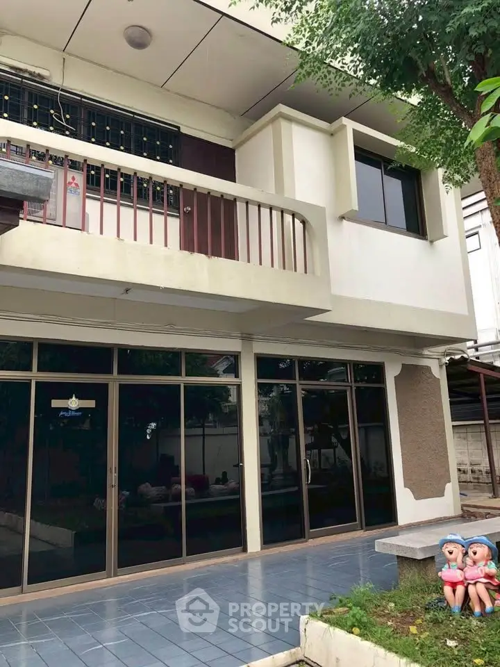 Charming two-story home with balcony and spacious front patio, perfect for family gatherings.