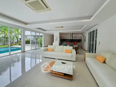 Spacious modern living room with pool view and open kitchen layout.