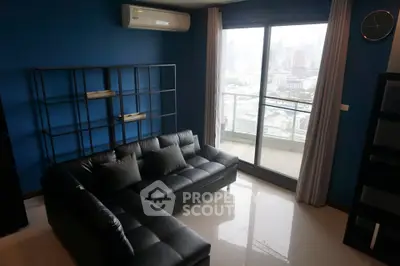 Modern living room with black leather sofa and city view balcony.
