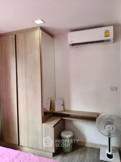 Modern bedroom with built-in wardrobe, air conditioning, and sleek wooden furniture.