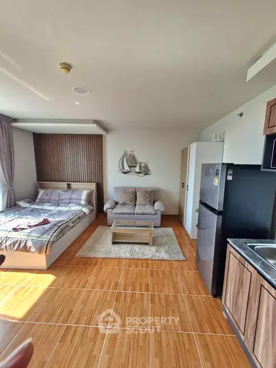 Modern studio apartment with cozy living area and kitchen, featuring wooden flooring and stylish decor.