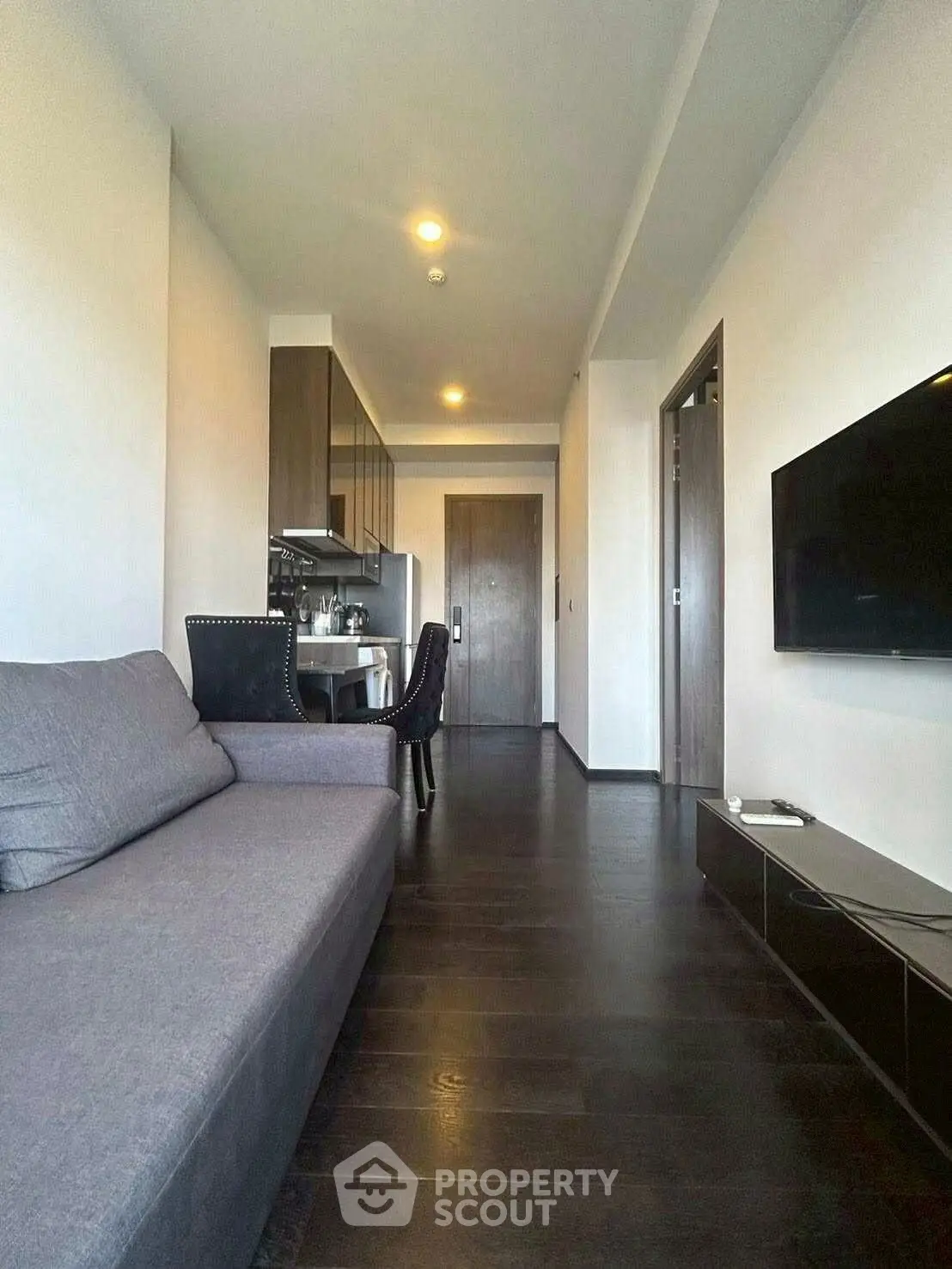 Modern living room with sleek furniture and open kitchen layout in a stylish apartment.