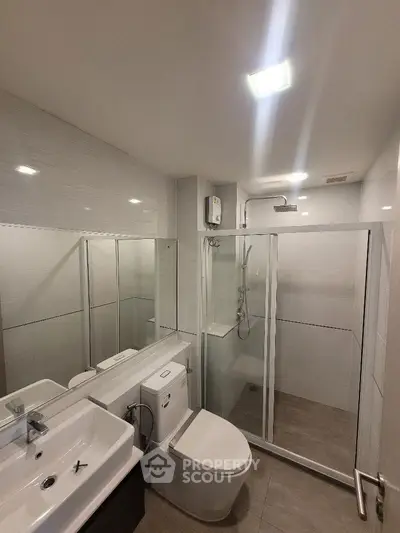 Modern bathroom with glass shower enclosure and sleek fixtures.